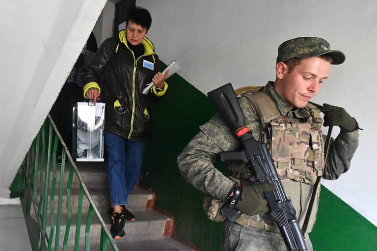 Abstimmung im Zeichen des Sturmgewehrs: In Donezk werden die Stimmzettel für das Scheinreferendum zu den Menschen nach Hause gebracht – in Begleitung von bewaffneten Soldaten. (Quelle: RIA Novosti/imago images)