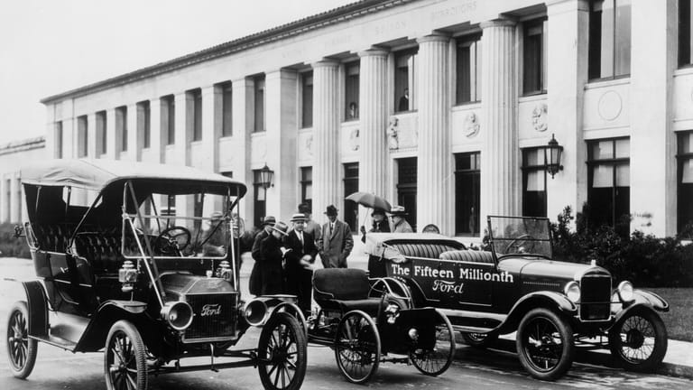 27.09.1908: Das Auto, das Amerika mobil machte — Als am 27. September 1908 die letzten Schrauben am ersten jemals gefertigten Ford Modell T festgezogen wurden, war das gesamte Automobil noch an einem Platz in der Halle zusammengeschraubt worden. Bald war der Wagen jedoch so beliebt, dass Firmenpatriarch Henry Ford die Produktion auf das Fließband verlegte. Bis zu 9.000 Stück konnten so an einem Tag das Werk verlassen. Um die Produktion zu beschleunigen, gab es das begehrte Auto auch nur in einer einzigen Farbe: Schwarz. Die Umstellung wirkte sich günstig auf den Preis aus: von 850 US-Dollar fiel er später auf 370 US-Dollar. Mit 15 Millionen Exemplaren zwischen 1908 und 1927 wurde das auch Tin Lizzie genannte Modell T zum meistverkauften Automobil der Welt. Das erste Exemplar befindet sich auf diesem Bild von 1927 links. (Quelle: akg-images/dpa)